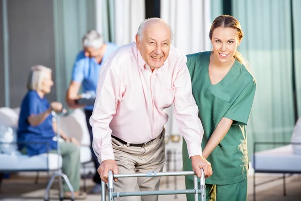 A man and woman in scrubs with a walker.