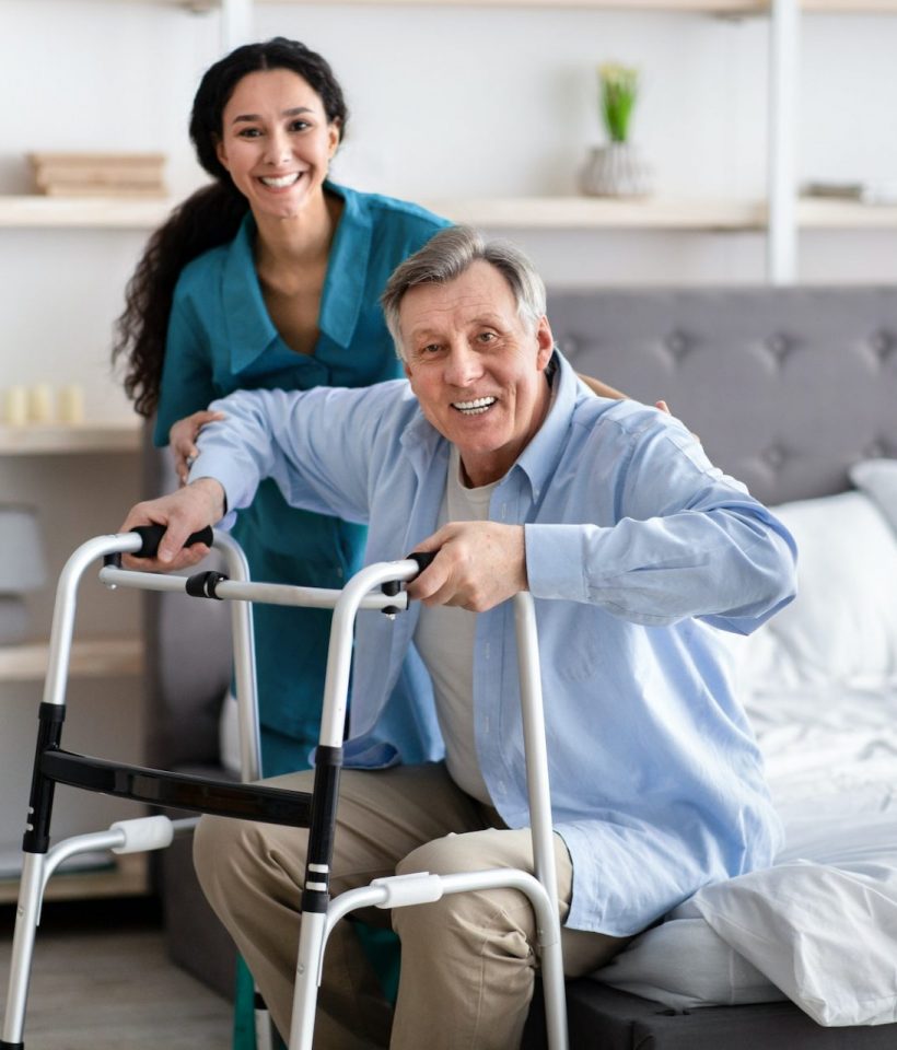 A man and woman are smiling while holding onto a walker.