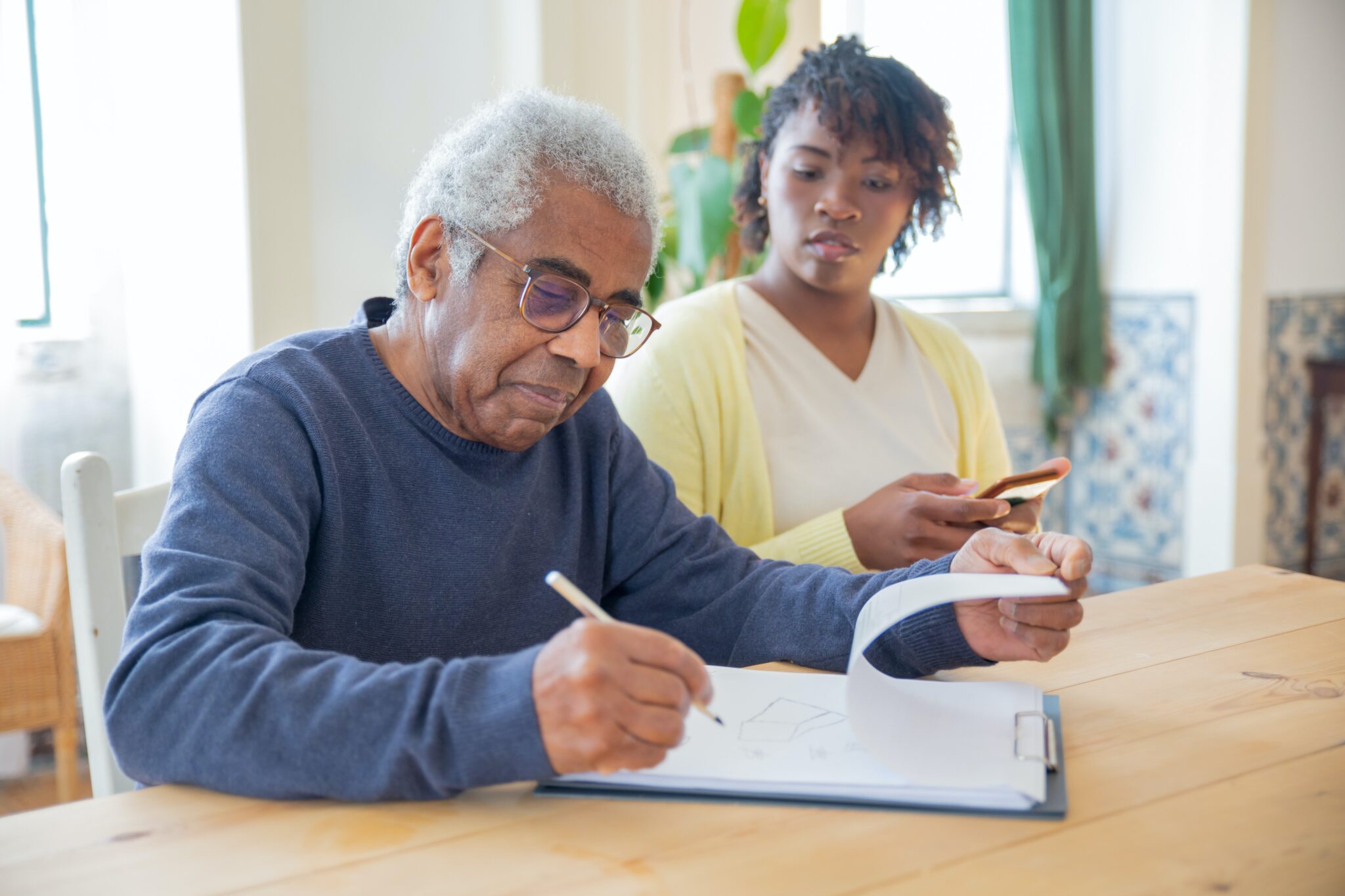 A man and woman sitting at a table writing on paper.