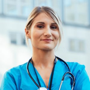 A woman in blue scrubs with a stethoscope around her neck.