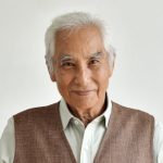 A man with white hair and wearing a vest.