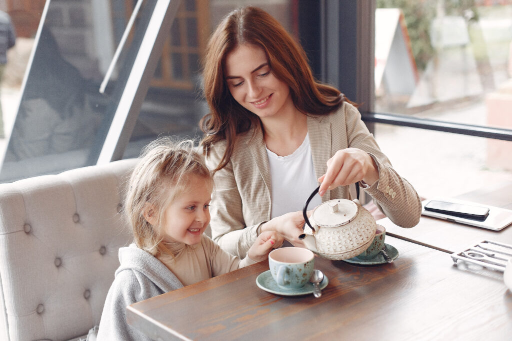 A woman and child sitting at a table with tea.