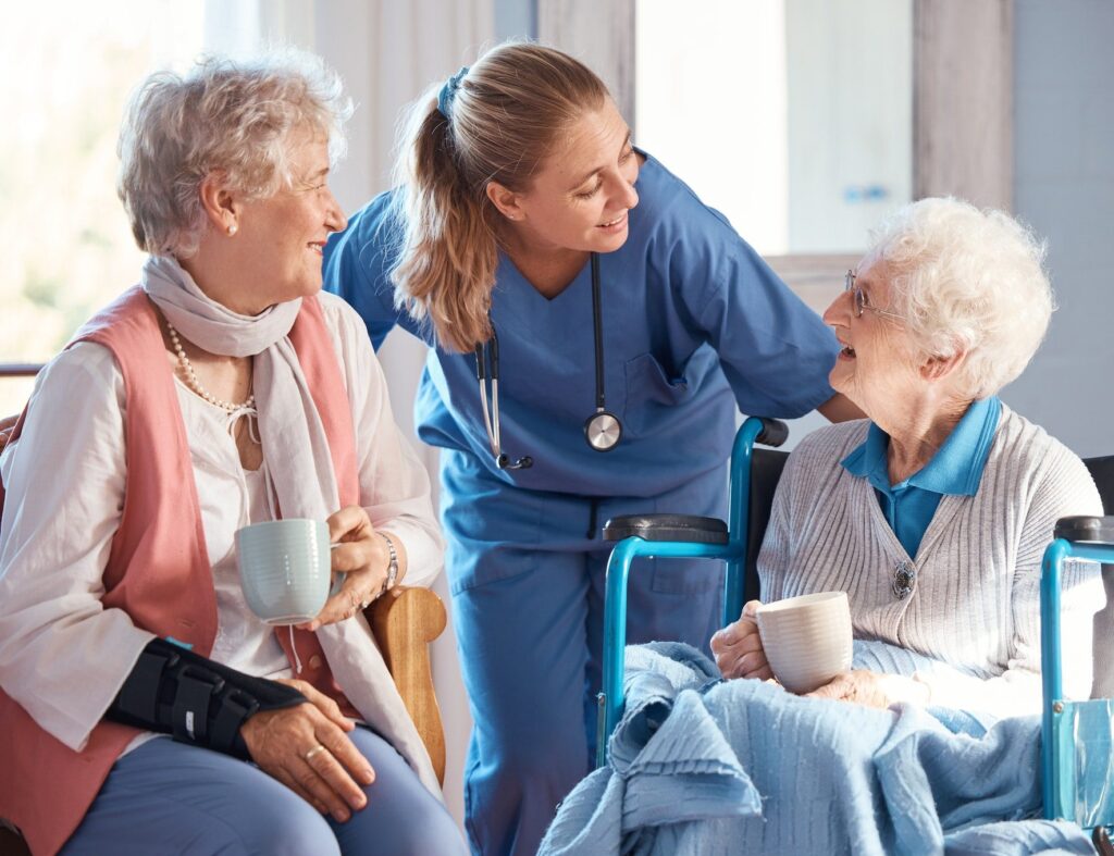 A nurse talking to two elderly women in a room.