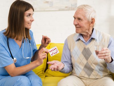 A nurse and an old man sitting on a couch